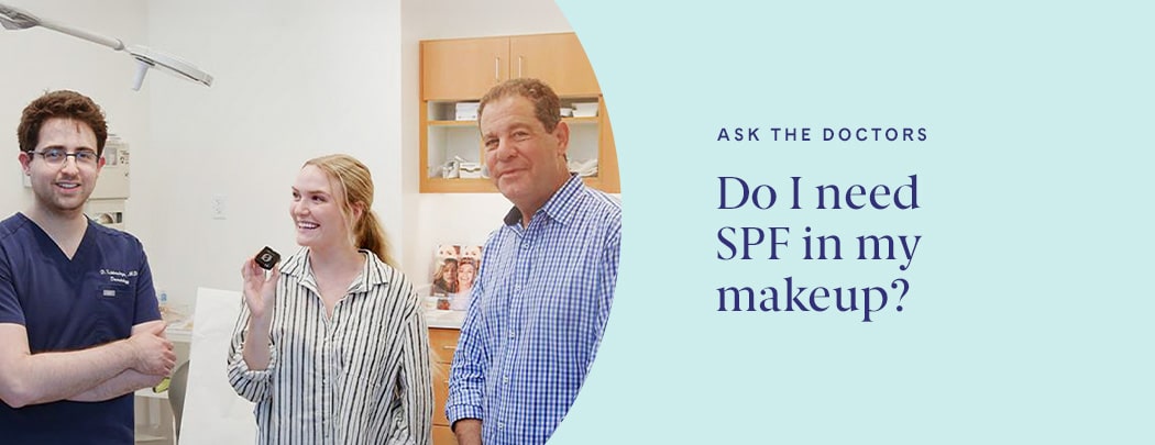 Three people stand candidly in a doctor's office smiling at one another or the camera.