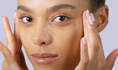 Young woman applying skin care to her face