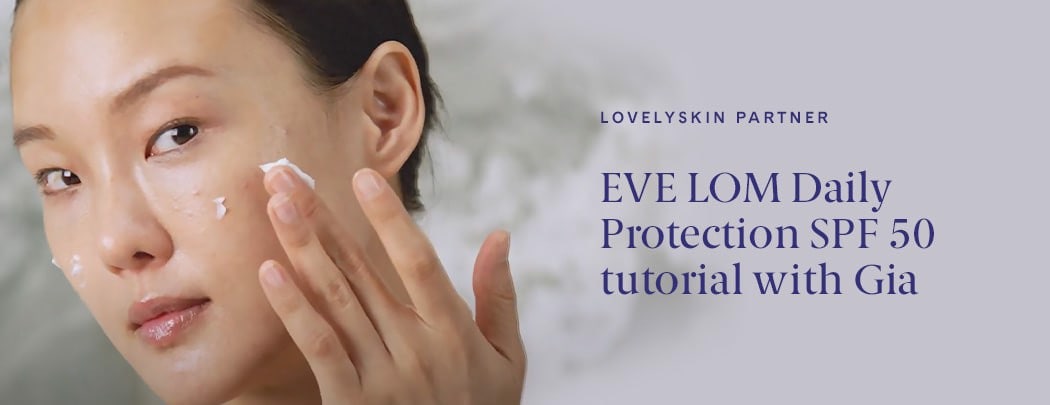 A woman of asian descent applying EVE LOM Daily Protection SPF 50 Sunscreen to her face.