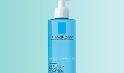 A blue bottle with a white pump of La Roche-Posay Toleriane Purifying Foaming Cleanser on a light blue background