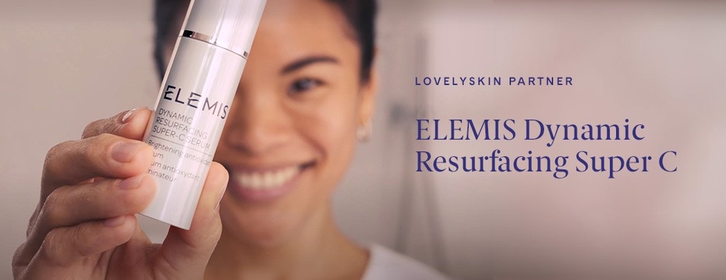 A woman holding a white tube of ELEMIS Dynamic Resurfacing Super C in front of her face at an angle.