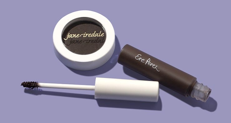 jane iredale brow powder in a round container and Ere Perez brow gel with the top lid off, on a purple background.