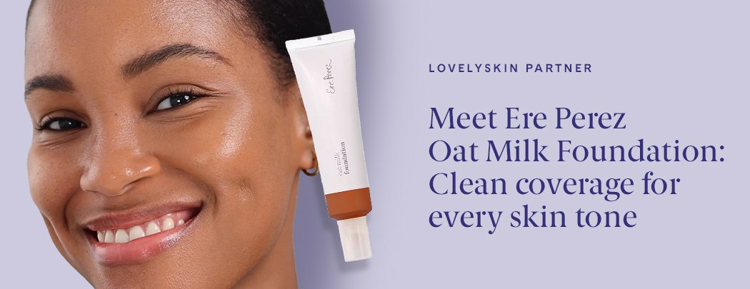 A woman with a deep skin tone smiles at the camera. Her skin looks dewy and radiant.