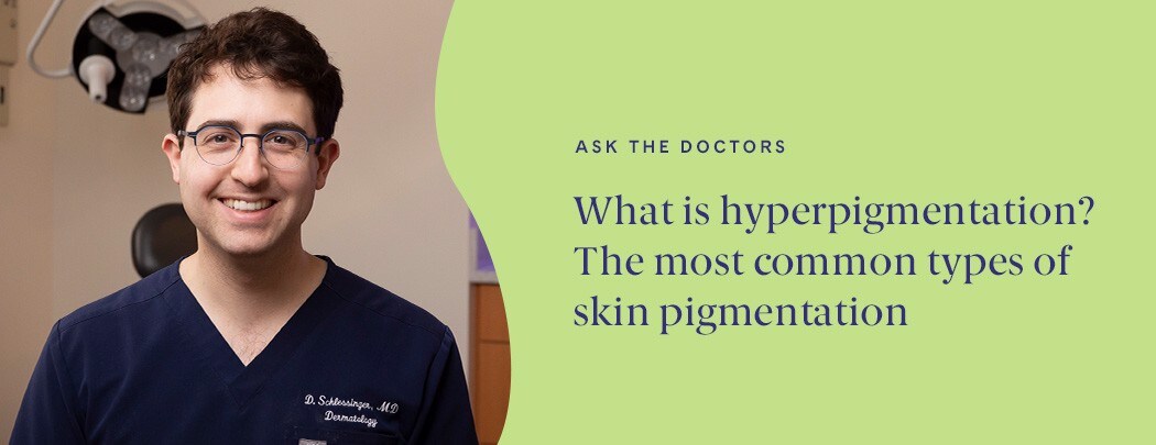 A young dermatologist with glasses, fair skin and dark brown hair wearing navy blue scrubs smiles at the camera.