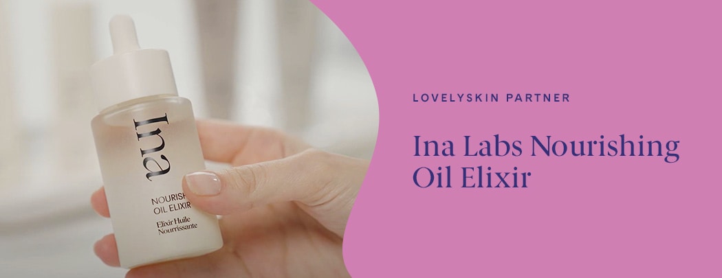 A person with fair skin and polished nails holds a bottle of Ina Nourishing Oil Elixir.