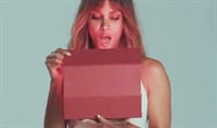 Halle Berry looks into a box with a surprised look on her face as red light shines onto her skin.