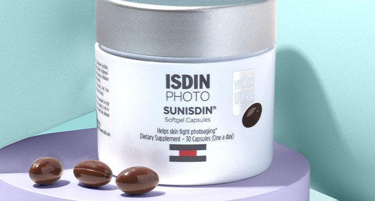 ISDIN Photo Sunisdin skin care supplements in a jar in front of a blue background.