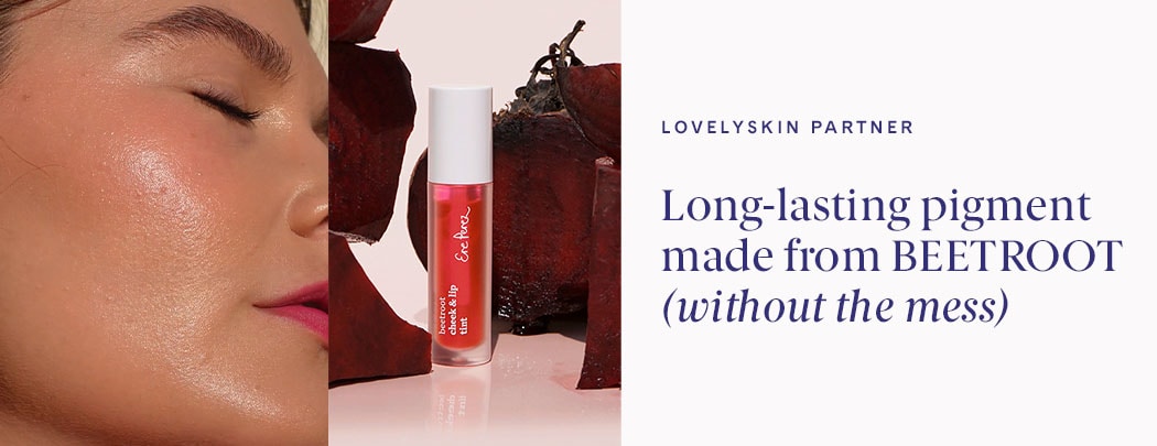 A woman with medium skin tone and brown hair shows her lips and cheeks with a pink hue. A tube of Beetroot Cheek & Lip Tint is pictured next to her.