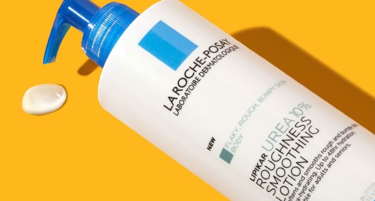 A blue and white bottle of La Roche-Posay Lipikar Urea 10% Roughness Smoothing Lotion on an orange background.