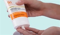 One hand dispensing sunscreen lotion into another hand
