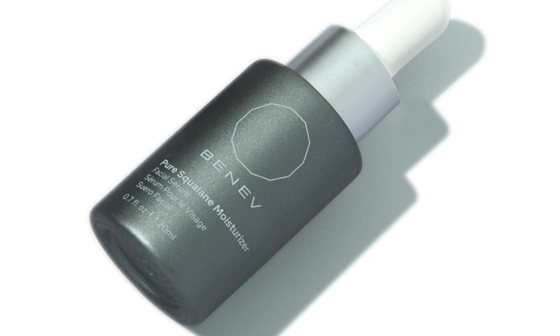 White moisturizer bottle with blue label that reads "Pure Squalane Moisturizer" laying on light green background.