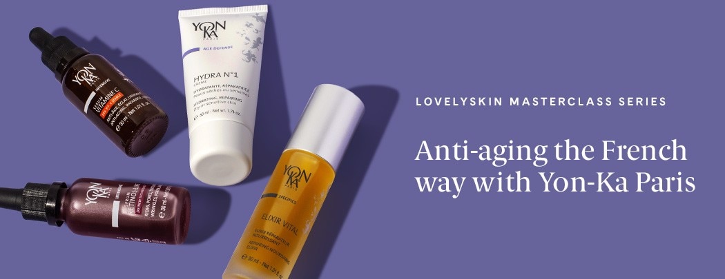 Four products, one in a white tube, two in clear glass bottles, and one in a brown glass bottle, lay on a medium purple background.