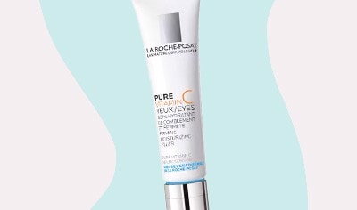 A white tube of La Roche-Posay Pure Vitamin C Eye Cream with a silver lid on a blue and gray background.