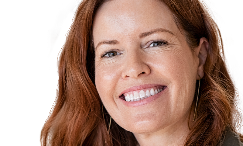 Woman with red hair smiling and looking off camera.