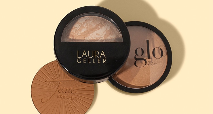 Three powder bronzer products stacked together on a yellow background.  One is opened to show texture and the jane iredale logo imprint.