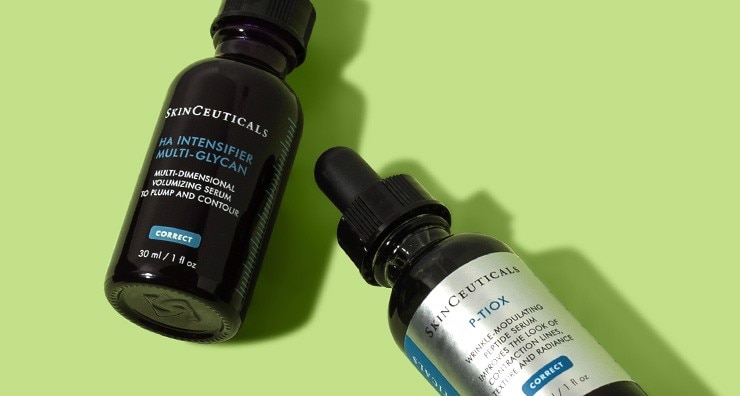 Dark brown glass serum bottles of SkinCeuticals P-TIOX and HA Intensifier Multi-Glycan placed diagonally on a light green background.