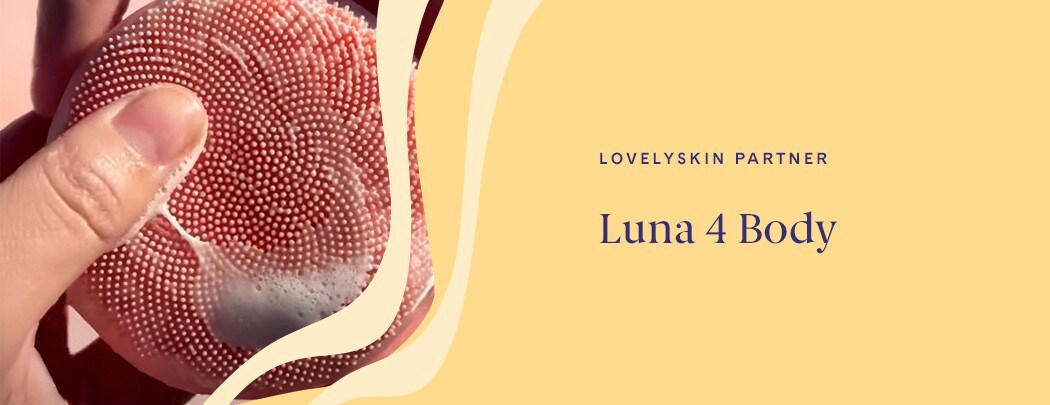 A hand holding a coral device with silicone touchpoints and soap suds.