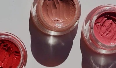 Ere Perez Carrot Colour Pots sit on a grey background. The pots have indents in them as if used with a makeup tool.