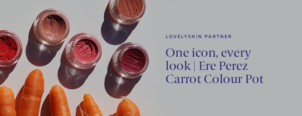 Ere Perez Carrot Colour Pots sit on a grey background with carrots beneath them. The pots have indents in them as if used with a makeup tool.