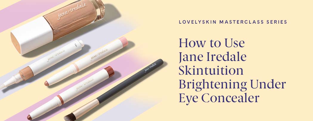 Five Jane Iredale products lay next to one another in an aesthetic line. There's a foundation, a concealer, two eyeshadow sticks, and a makeup brush.