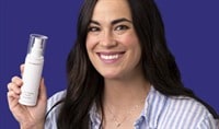 A woman with an olive skin tone and dark brown hair holds a bottle of SkinMedica HA5 Hydra Collagen Facial Mist while smiling at the camera.