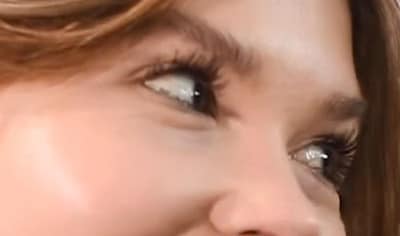 A woman with defined lashes looks off into the distance.