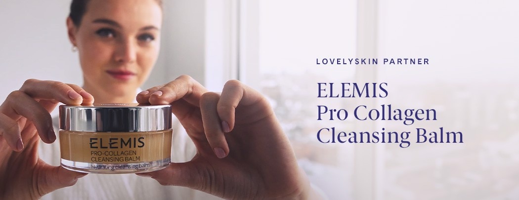 A woman smiling softly and holding a jar of ELEMIS Pro Collagen Cleansing Balm in front of her face.l