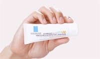 A male hand with medium skin tone holding a bottle of La Roche-Posay Cicaplast Baume B5 Soothing Multi-Purpose Cream SPF 50