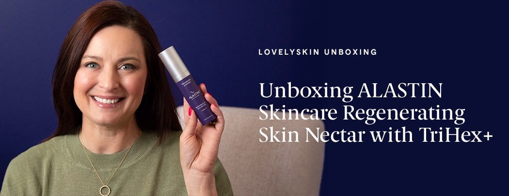 A woman with a light, neutral skin tone and dark brown hair holds a bottle of ALASTIN Skin Nectar with TriHex Plus while smiling at the camera.