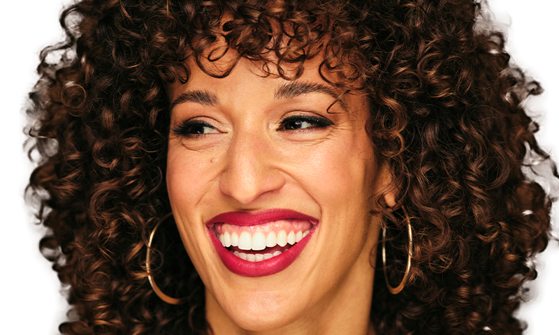 Woman with curly hair smiling and looking off camera