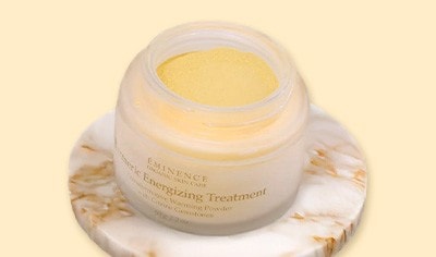 A glass pot of Eminence Organics Tumeric Energizing Treatment on a marbled tray