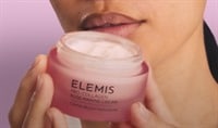 An asian woman holding a jar of ELEMIS Pro Collagen Rose Marine Cream in front of her face, just below her lips.