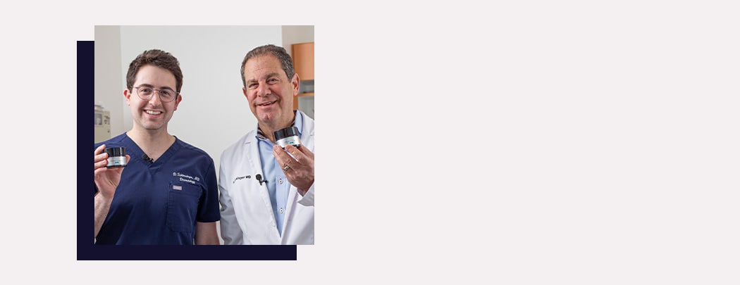 Two dermatologists, one in his 60s and one in his 30s, stand next to one another smiling as they hold SkinCeuticals P-TIOX Micro-Peptide Cream.