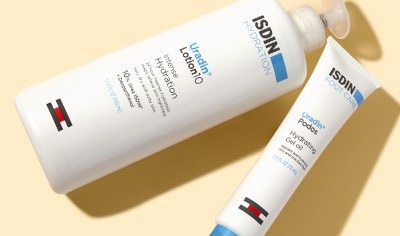 A bottle of ISDIN body lotion and a tube of ISDIN foot gel featuring urea on a beige background.