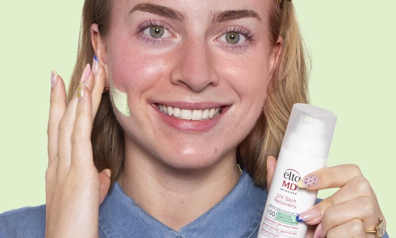 Woman applying green sunscreen to her face reducing redness