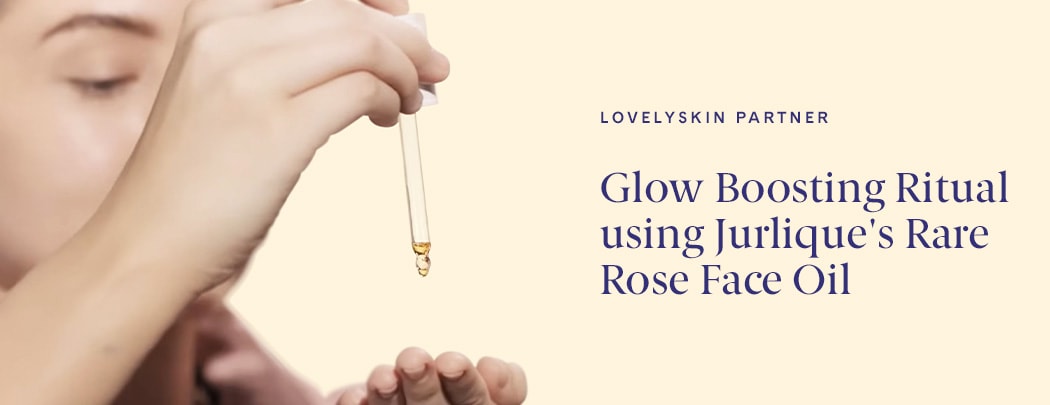 A woman with fair skin holds a dropper of Jurlique Rare Rose Facial Oil above her palm.