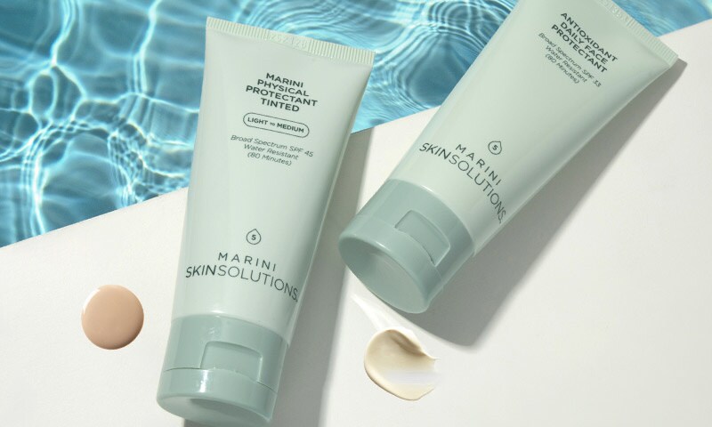 Marini SkinSolutions sunscreens sitting on the edge of a pool with swatches