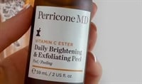 A hand holding a bottle of PerriconeMD skin care.