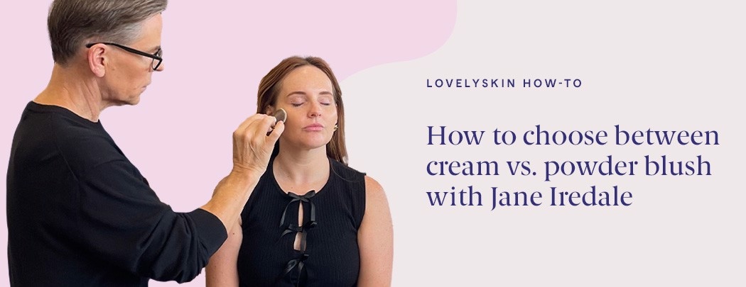 An older gentleman with glasses applies blush to a woman with fair skin and red hair.