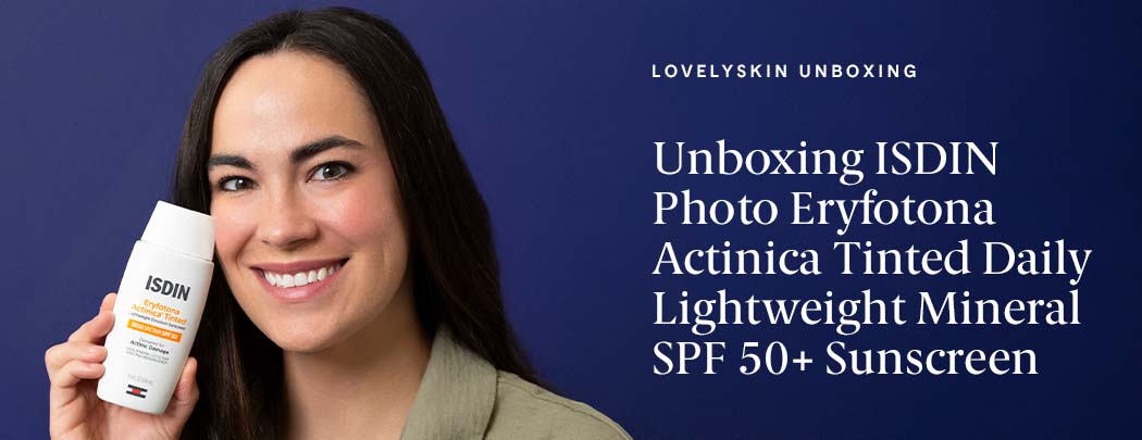 A woman with olive toned skin and dark hair holds a bottle of ISDIN Photo Eryfotona Actinica Tinted Daily Lightweight Mineral SPF 50+ while smiling.