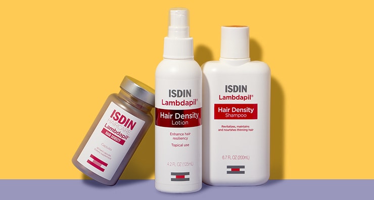 Four bottles of ISDIN hair loss products arranged on a yellow background