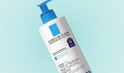 White bottle of La Roche-Posay Lipikar AP+M Triple Repair Body & Face Moisturizer For Dry Skin with a blue pump on a blue background.