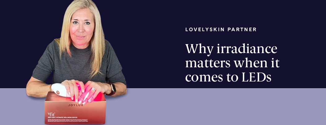 A woman with a light skin tone, brown eyes and blonde hair looks at the camera while holding a Joylux vFit device.