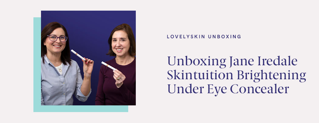 Two women, one in a dark purple shirt and one in a light blue shirt, hold Jane Iredale Skintuition Brightening Under Eye Concealer while smiling.