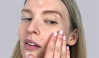 Young woman applying moisturizer to her face