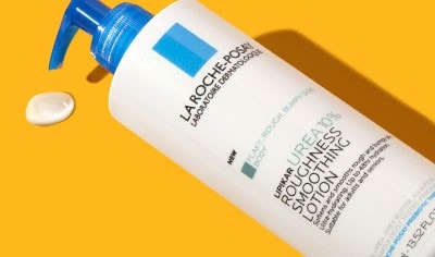 A blue and white bottle of La Roche-Posay Lipikar Urea 10% Roughness Smoothing Lotion on an orange background.