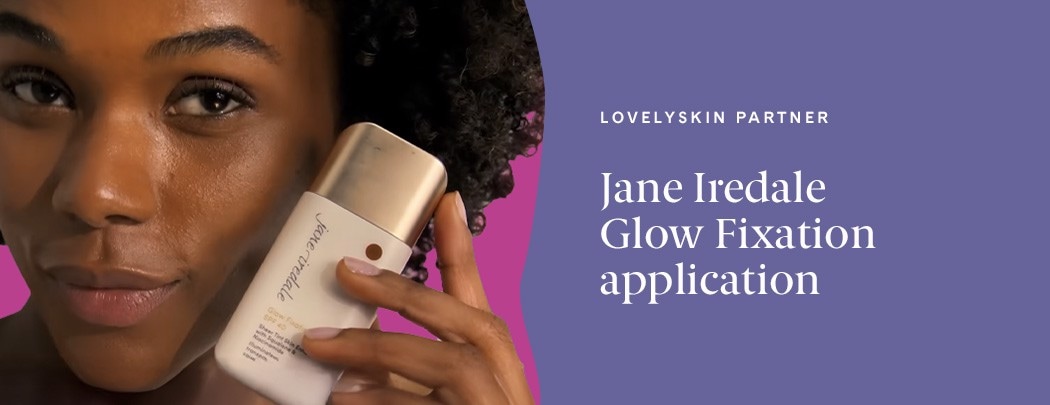 A woman with a deep skin tone and dark brown hair smiles while holding a bottle of Jane Iredale Glow Fixation.