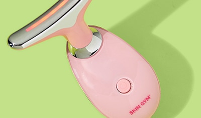 The light pink Skin Gym LitLift LED Facial Tool on a light green background.