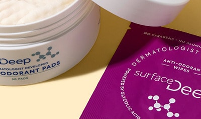 Surface Deep anti-odorant products: open pad container, wipes packet, and spray bottle on a yellow background