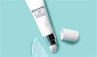 A tube of white lip cream on a turquoise background.  A swatch of the product is next to it.